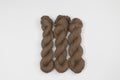 Three skeins of brown merino yarn arranged vertically on a plain white background.
