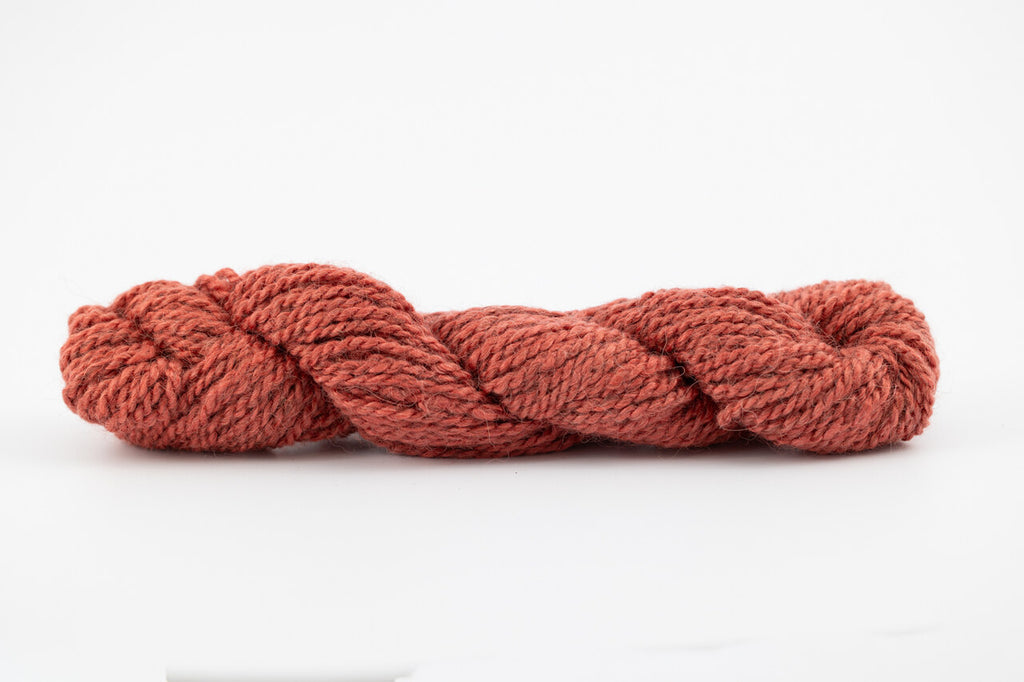 A skein of tesswater and muga silk naturally dyed with madder root to a brick red color.