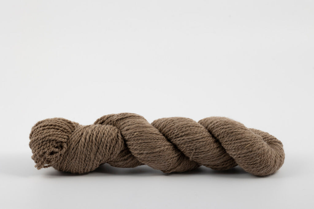A skein of medium brown twisted yarn photographed on a clean white studio background.