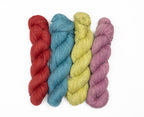 Four twisted yarn skeins in red, teal-blue, pale yellow, and dusty mauve, arranged vertically on a plain white background.