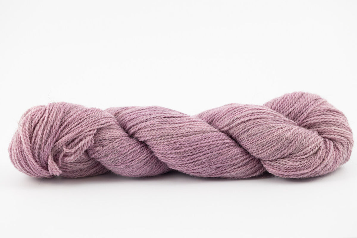 A skein of a blend of corriedale and gotland wool naturally dyed with cochineal to a lavender color.