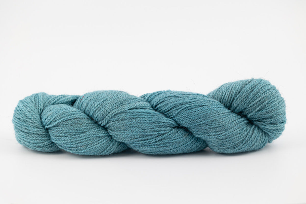 A skein of a blend of corriedale and gotland wool naturally dyed with indigo to a blue color.