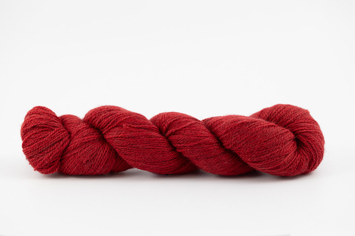 A skein of a blend of corriedale and gotland wool naturally dyed with madder root to a deep red color.