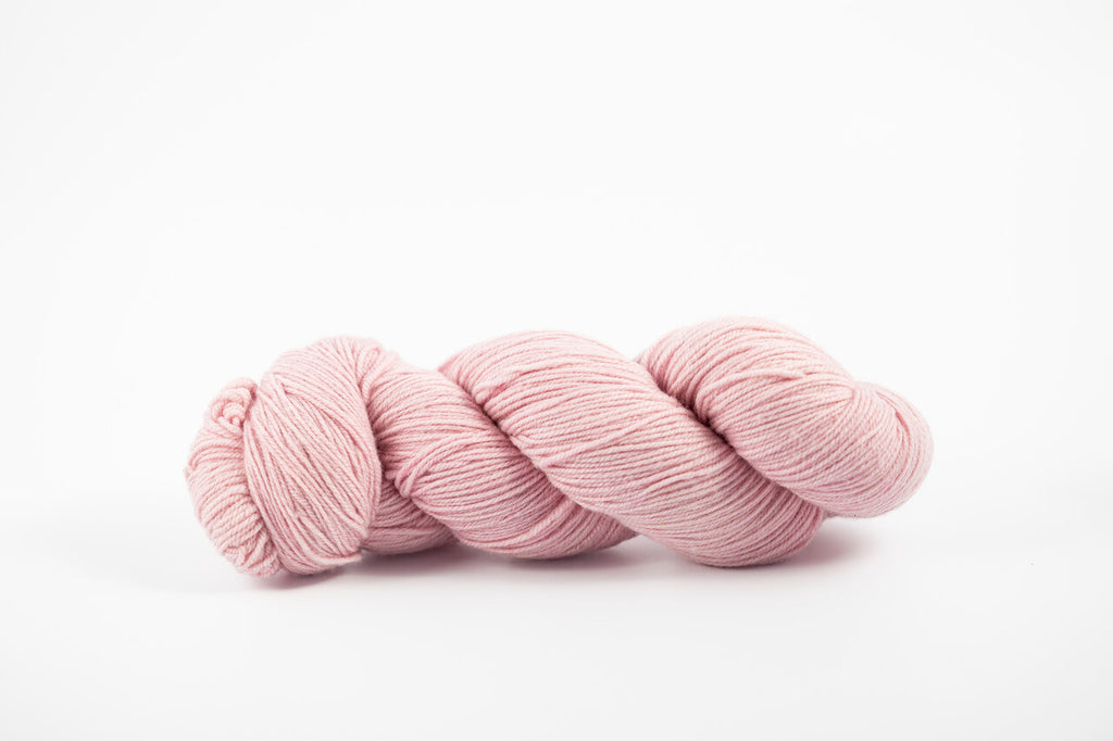 A skein of shaniko wool naturally dyed with cochineal to a light pink color.