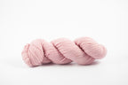 A skein of shaniko wool naturally dyed with cochineal to a light pink color.