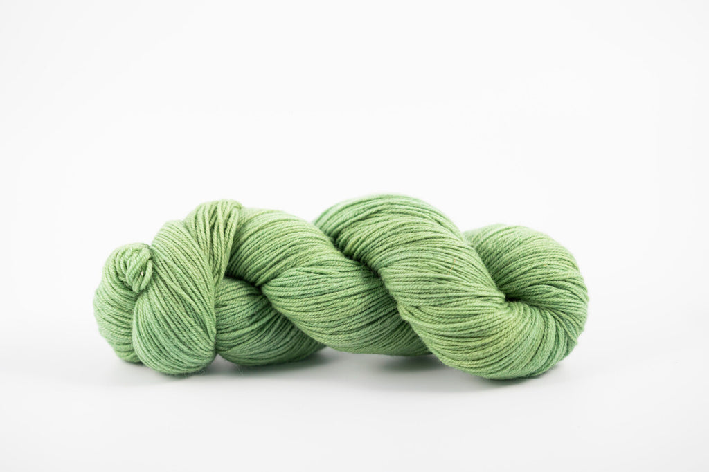 A skein of shaniko wool naturally dyed with indigo and marigold to a green color.