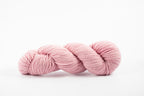 A skein of shaniko wool naturally dyed with cochineal to a light pink color.
