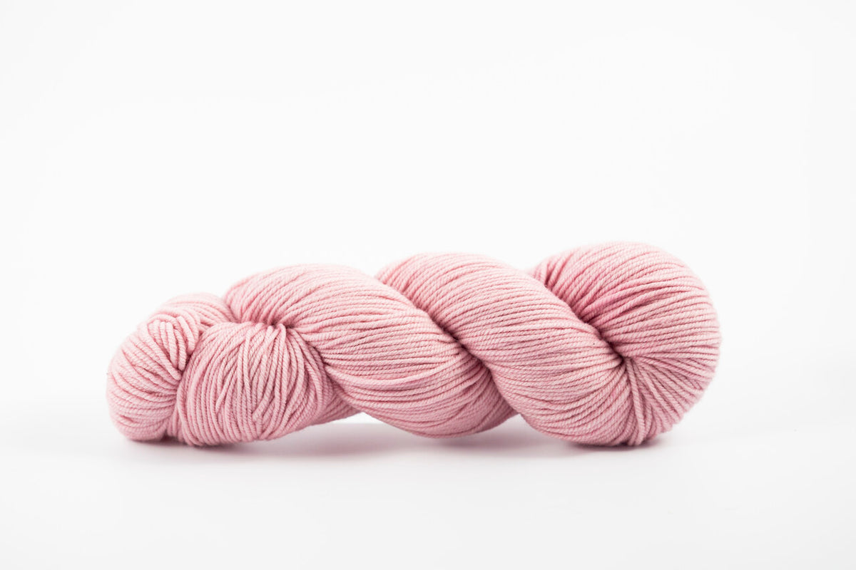 A skein of shaniko wool naturally dyed with cochineal to a light pink color.