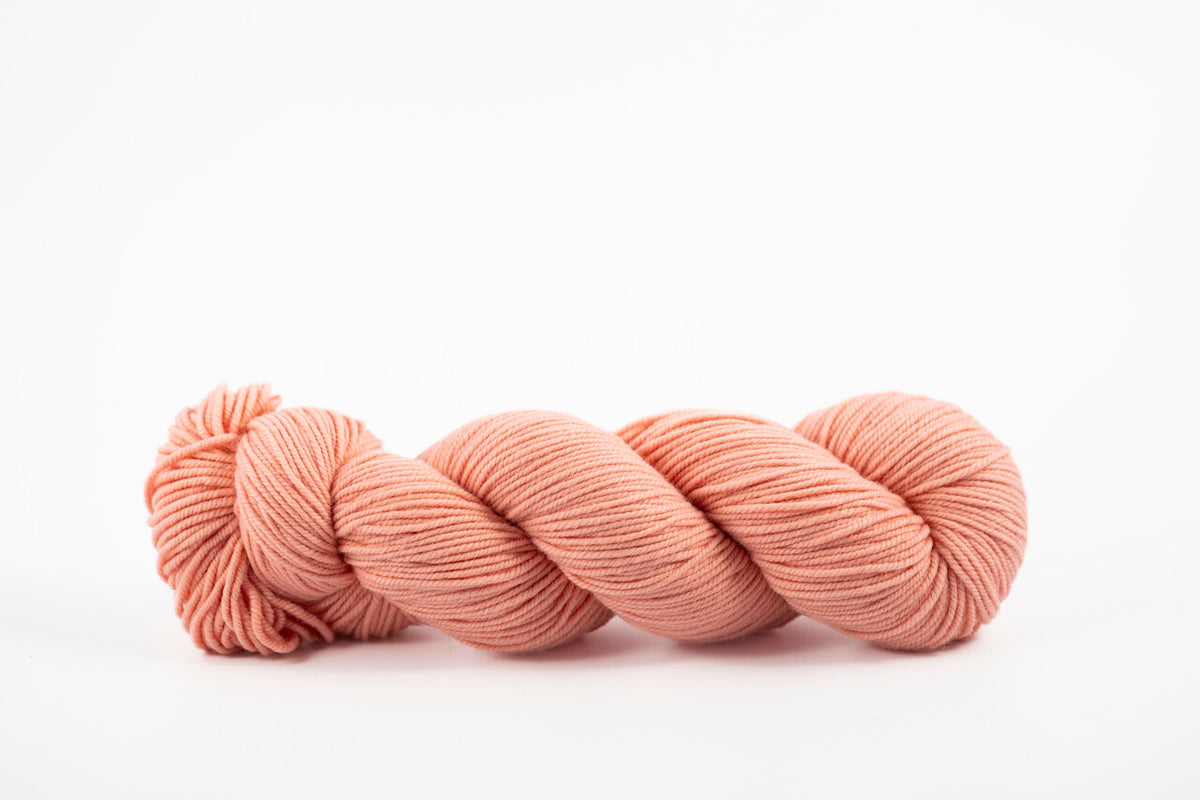 A skein of shaniko wool naturally dyed with madder root to a light coral color.