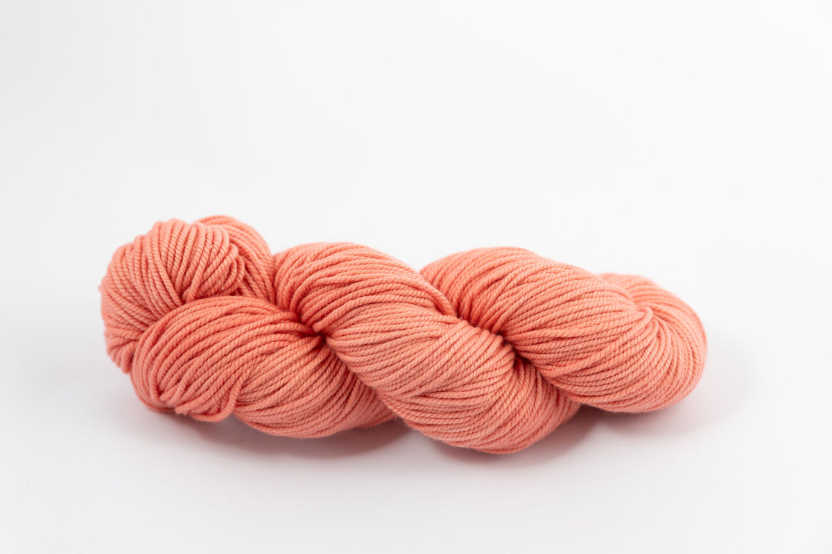 A coral skein of Shaniko wool and silk worsted weight yarn naturally dyed with madder root.