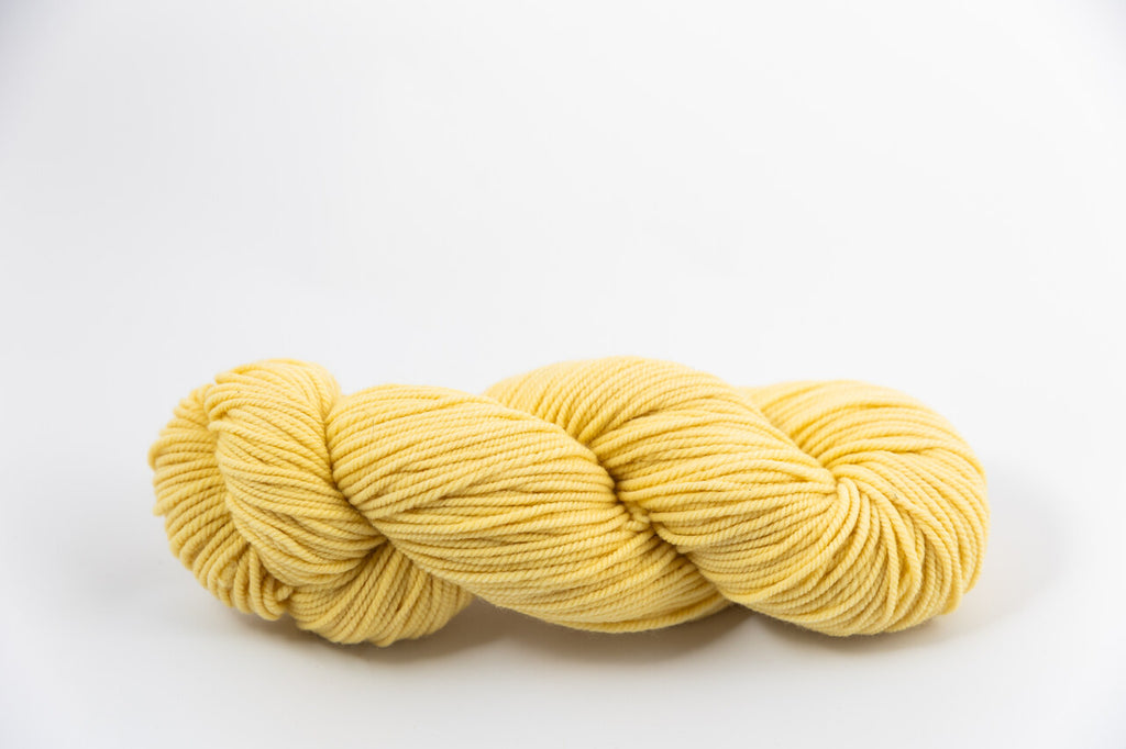 A light yellow skein of Shaniko wool and silk worsted weight yarn naturally dyed with marigold.