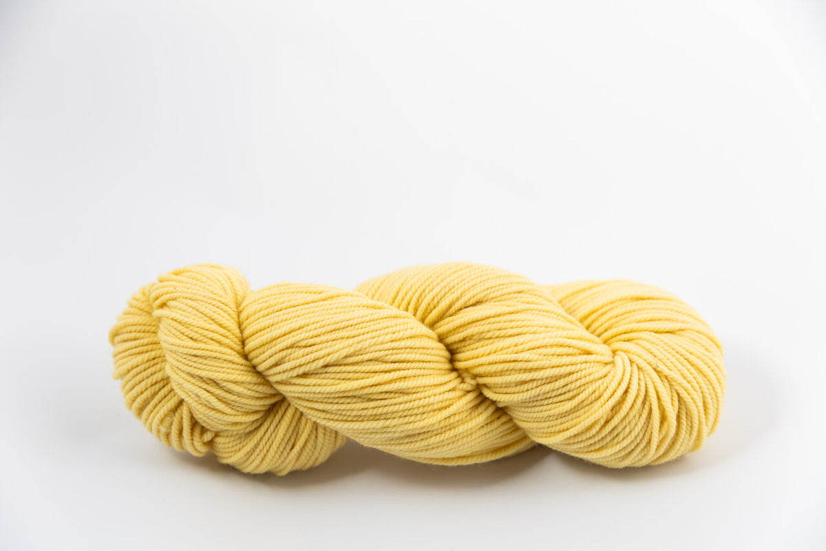 A light yellow skein of Shaniko wool and silk worsted weight yarn naturally dyed with marigold.