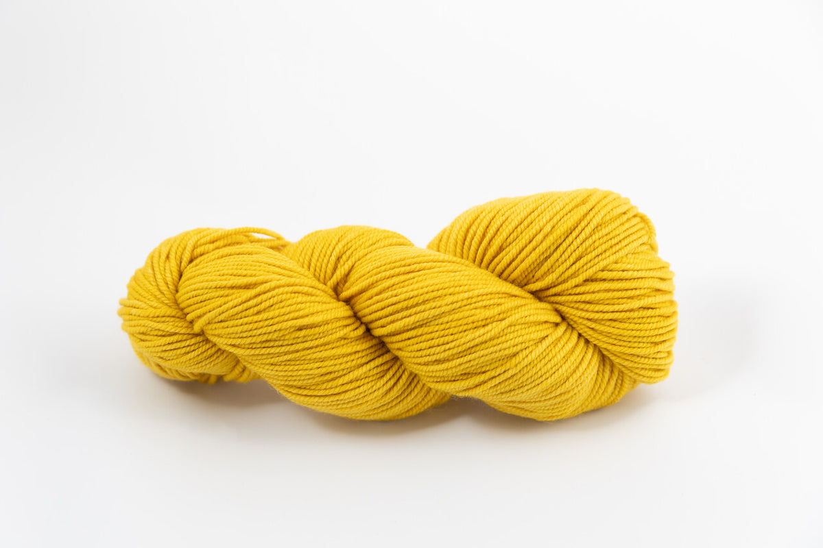 A yellow skein of Shaniko wool and silk worsted weight yarn naturally dyed with marigold.