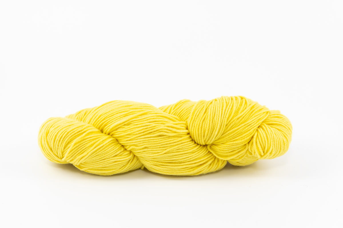 A bright yellow skein of Shaniko wool and silk yarn naturally dyed with weld.