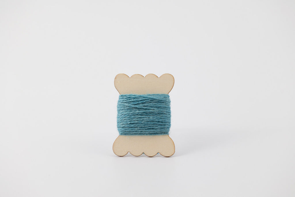 A blue spool of merino tussah silk embroidery thread naturally dyed with indigo.