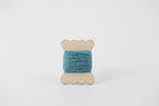 A blue spool of merino tussah silk embroidery thread naturally dyed with indigo.
