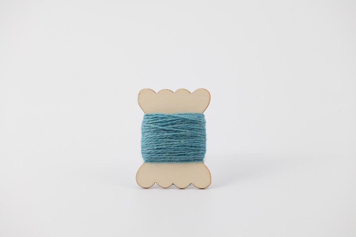 A blue spool of merino tussah silk embroidery thread naturally dyed with indigo.