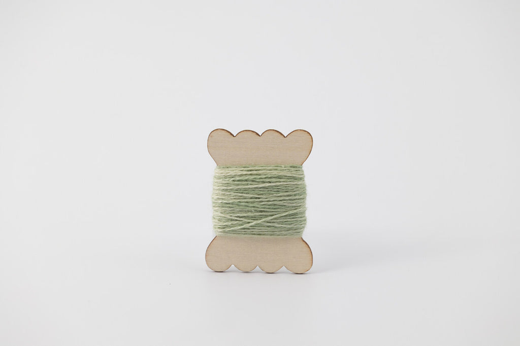 A light green spool of merino tussah silk embroidery thread naturally dyed with chlorophyllin.