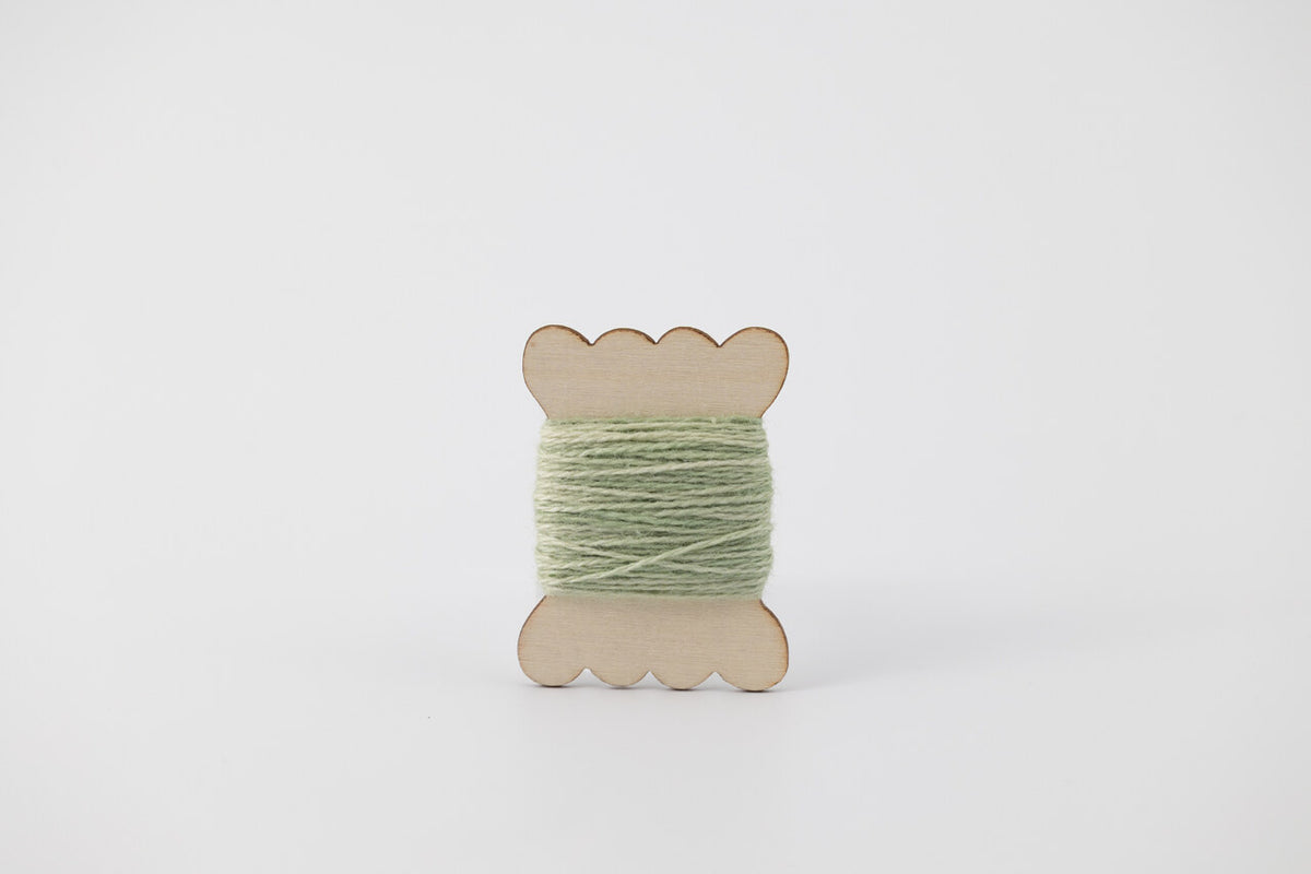 A light green spool of merino tussah silk embroidery thread naturally dyed with chlorophyllin.