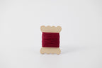 A dark pink spool of merino tussah silk embroidery thread naturally dyed with cochineal.