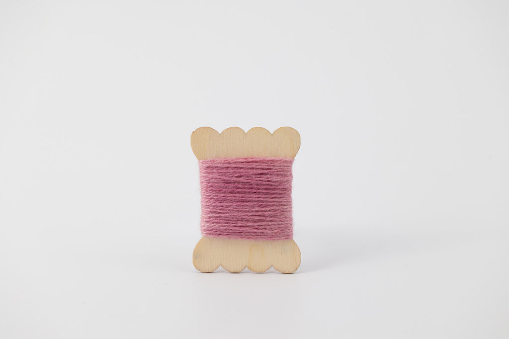 A light pink spool of merino tussah silk embroidery thread naturally dyed with cochineal.