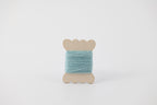A light blue spool of merino tussah silk embroidery thread naturally dyed with indigo.