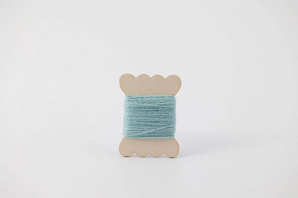 A light blue spool of merino tussah silk embroidery thread naturally dyed with indigo.