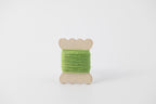 A bright green spool of merino tussah silk embroidery thread naturally dyed with weld and indigo. 