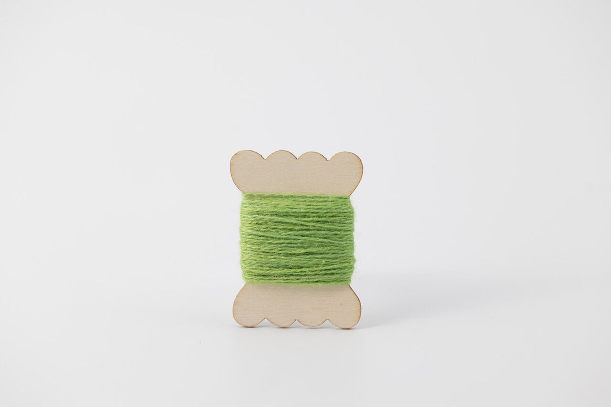 A bright green spool of merino tussah silk embroidery thread naturally dyed with weld and indigo. 