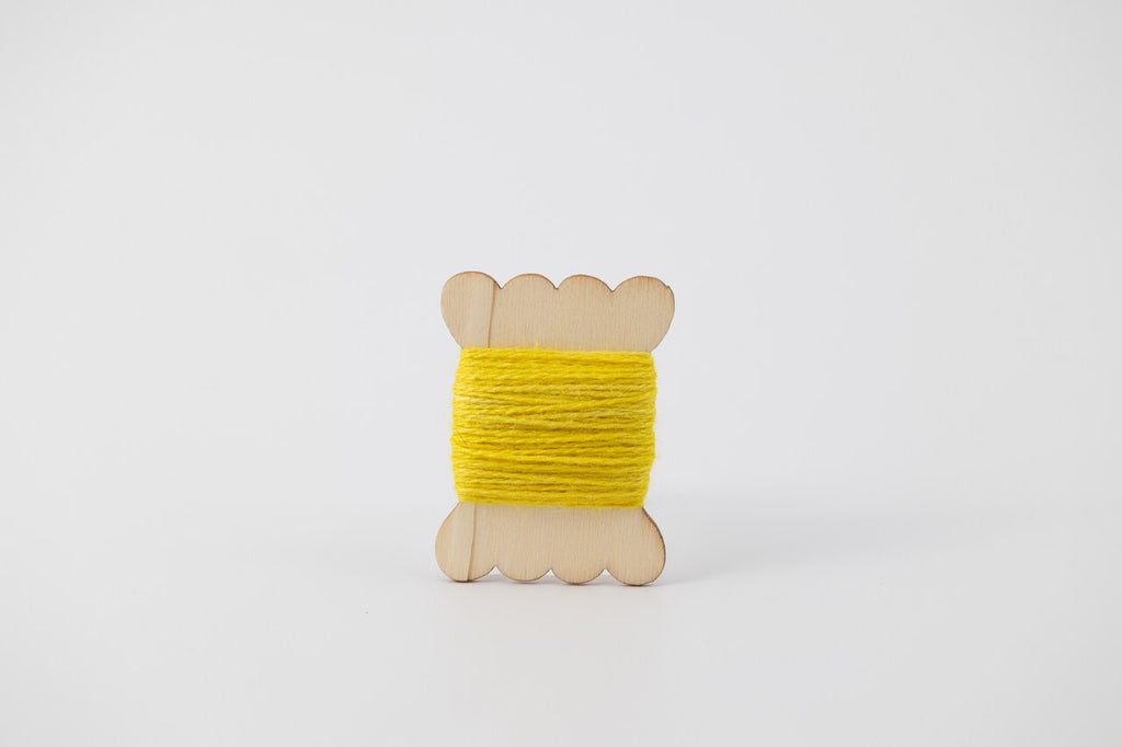 A bright yellow spool of merino tussah silk embroidery thread naturally dyed with weld.