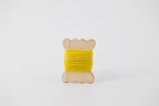 A bright yellow spool of merino tussah silk embroidery thread naturally dyed with weld.