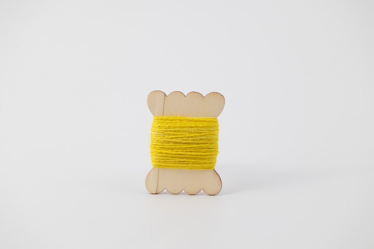A bright yellow spool of merino tussah silk embroidery thread naturally dyed with weld.