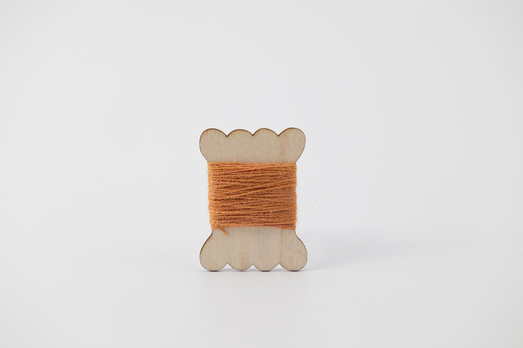A bobbin of tussah silk embroidery dyed with madder and marigold to an orange color.