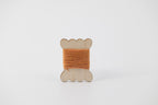 A bobbin of tussah silk embroidery dyed with madder and marigold to an orange color.