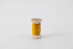 A spool of naturally dyed silk ribbon dyed with marigold to a golden yellow color.