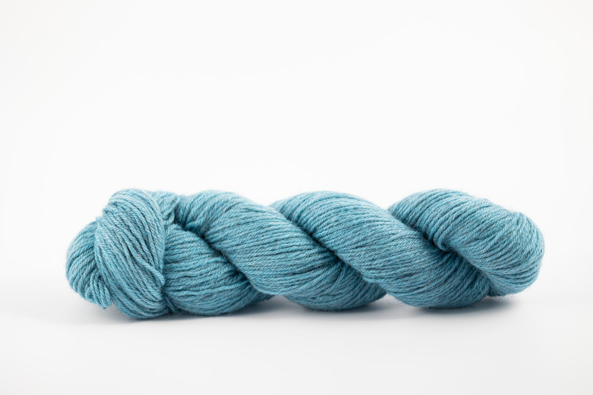 A skein of a blend of corriedale and gotland wool naturally dyed with indigo to a blue color.
