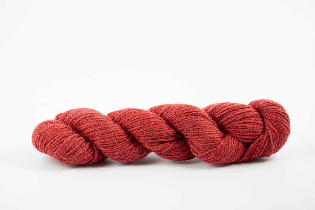 A skein of a blend of corriedale and gotland wool naturally dyed with madder root to a deep red color.